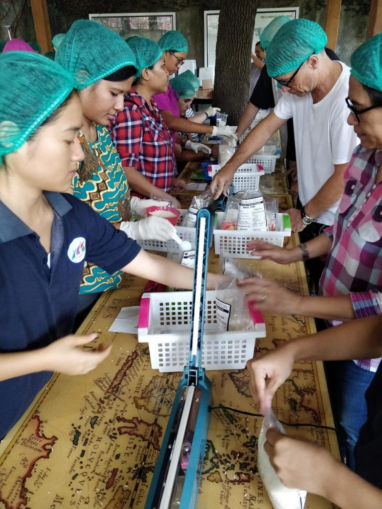 Volunteers wearing hairnets standing around a table