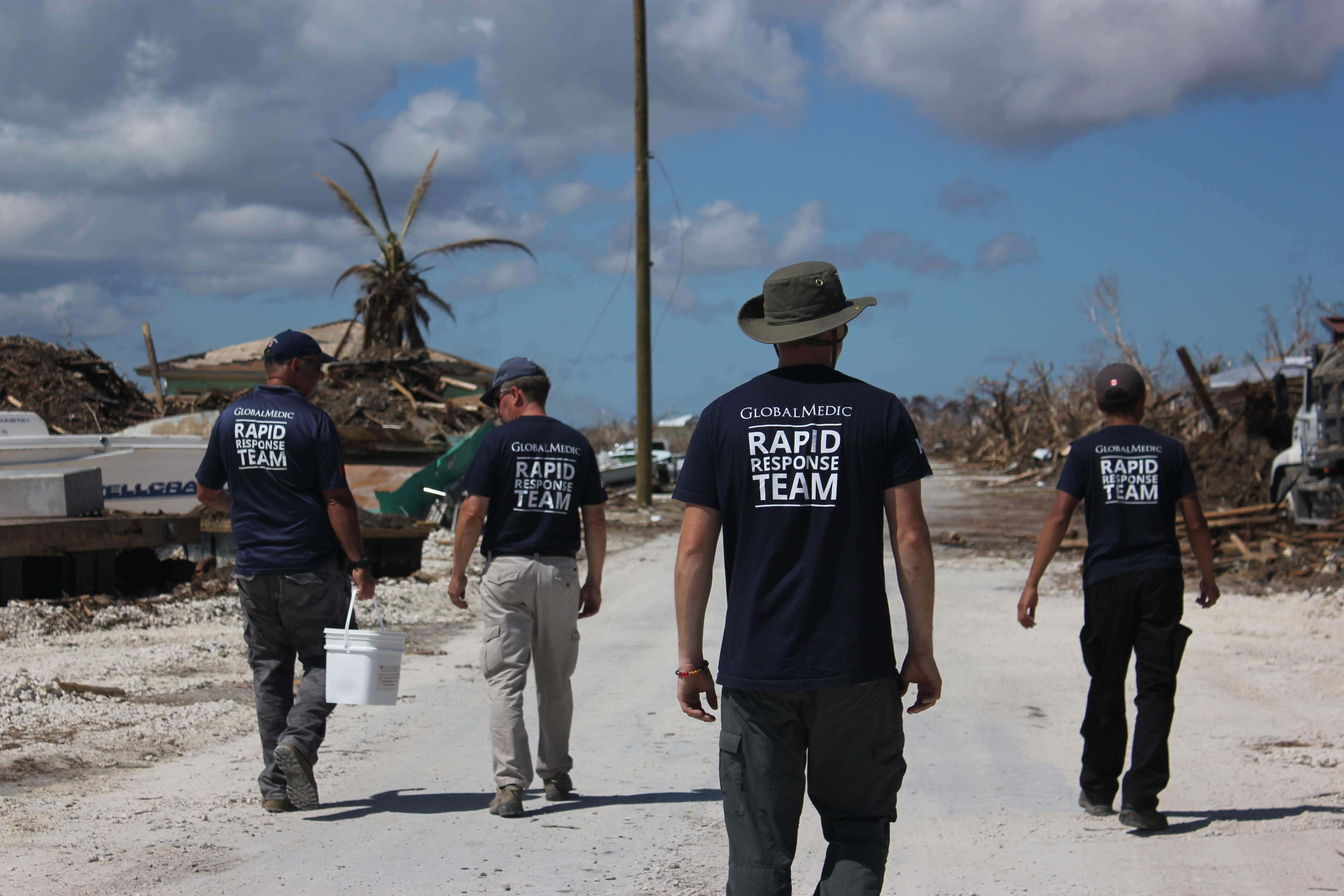 Rapid Response Team members walking between piles of rubble in Grand Bahama