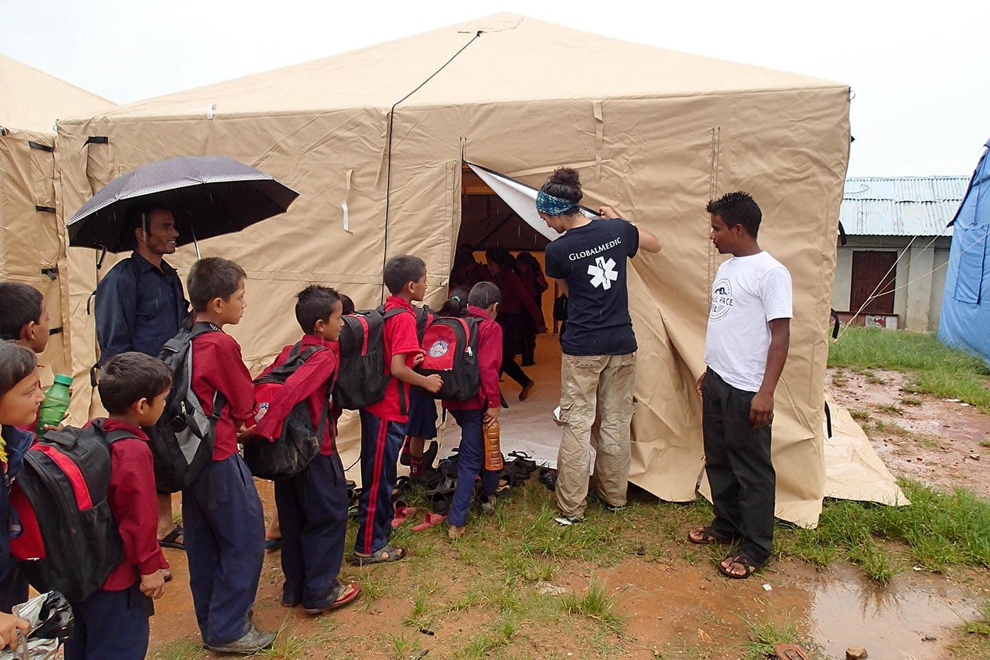 Rapid Response Team member leading a group of children into a Child Friendly Space constructed by GlobalMedic