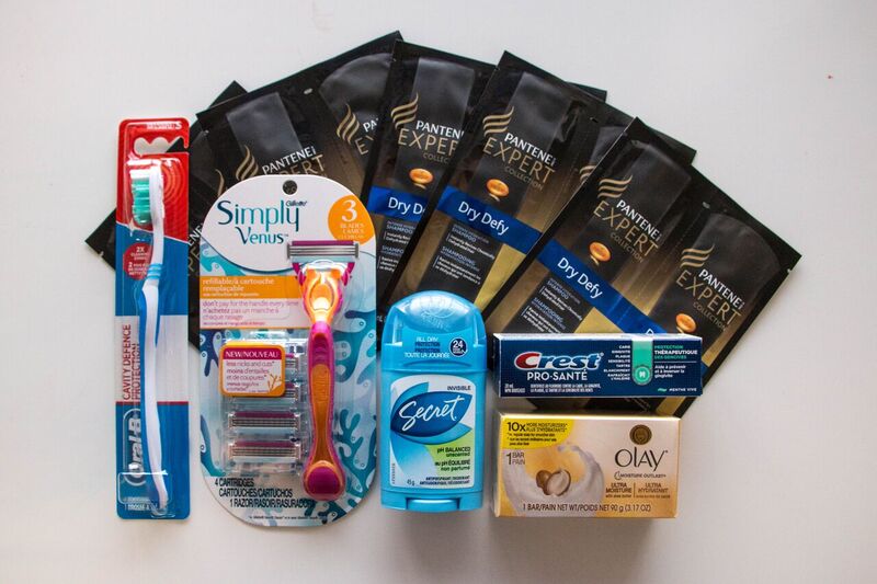 Items in a female hygiene kit, shampoo, conditioner, toothbrush, toothpaste, soap, deodorant, and razor