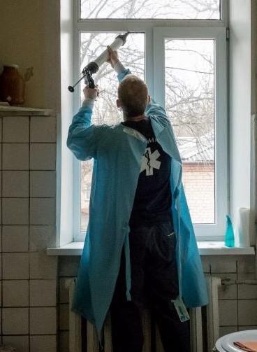 GM team member installing blast film on window in Ukraine