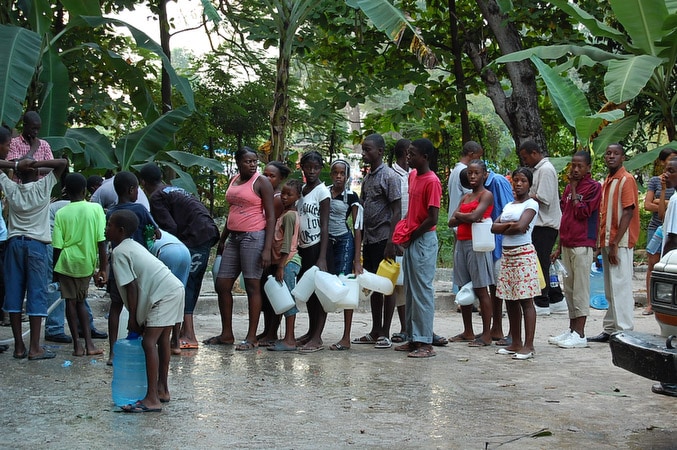A group of Haitians holding empty containers waiting to collect purified water