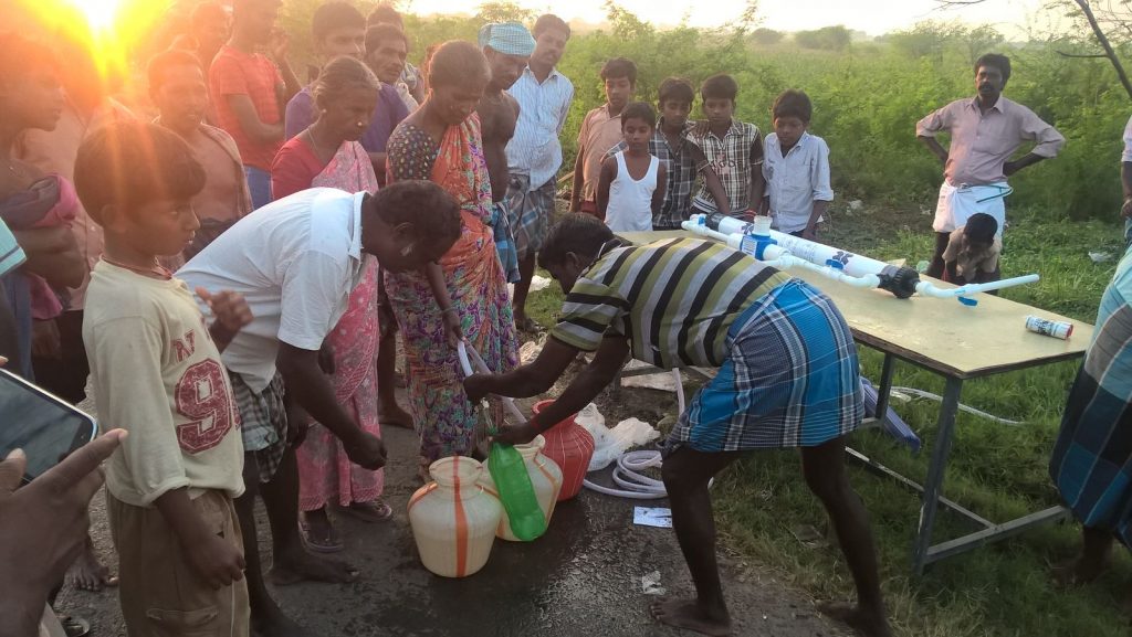 A group of people collecting water from an AP700 Community Water Filter