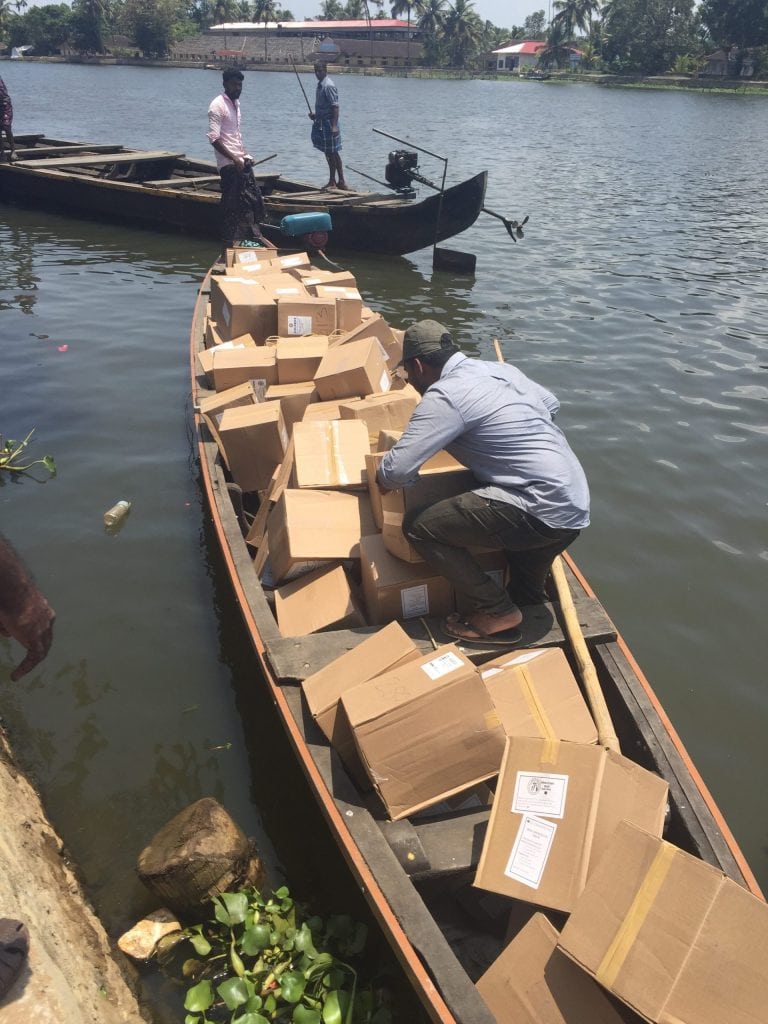 Household water purification units being loaded into a small boat