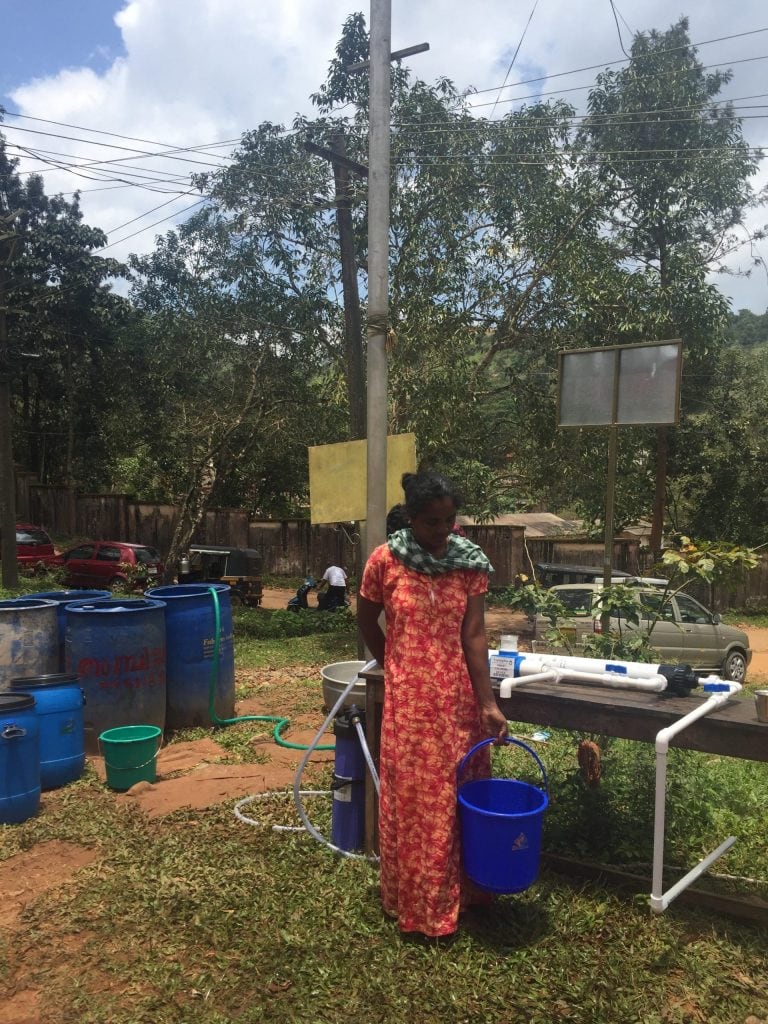 A woman collecting water from an AP700 community water filter
