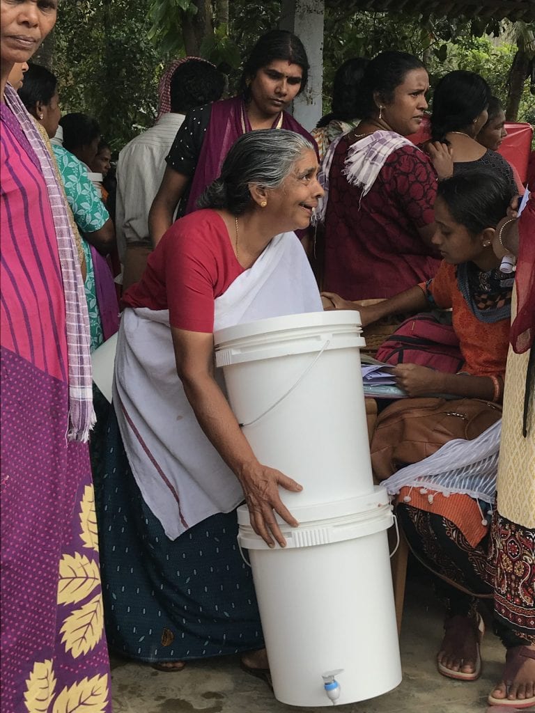 A woman receiving a household water purification unit