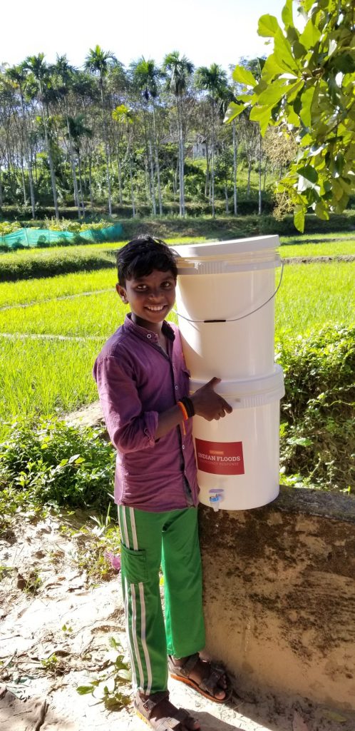 A young boy holding a household water purification unit