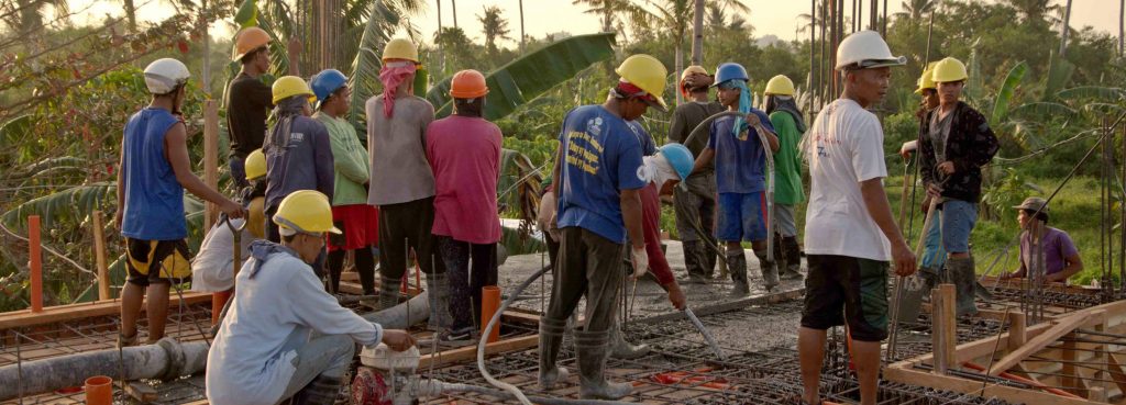 Local labourers pour cement for second floor slab
