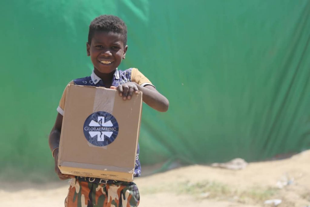 A child holding a box with a GlobalMedic logo on the front