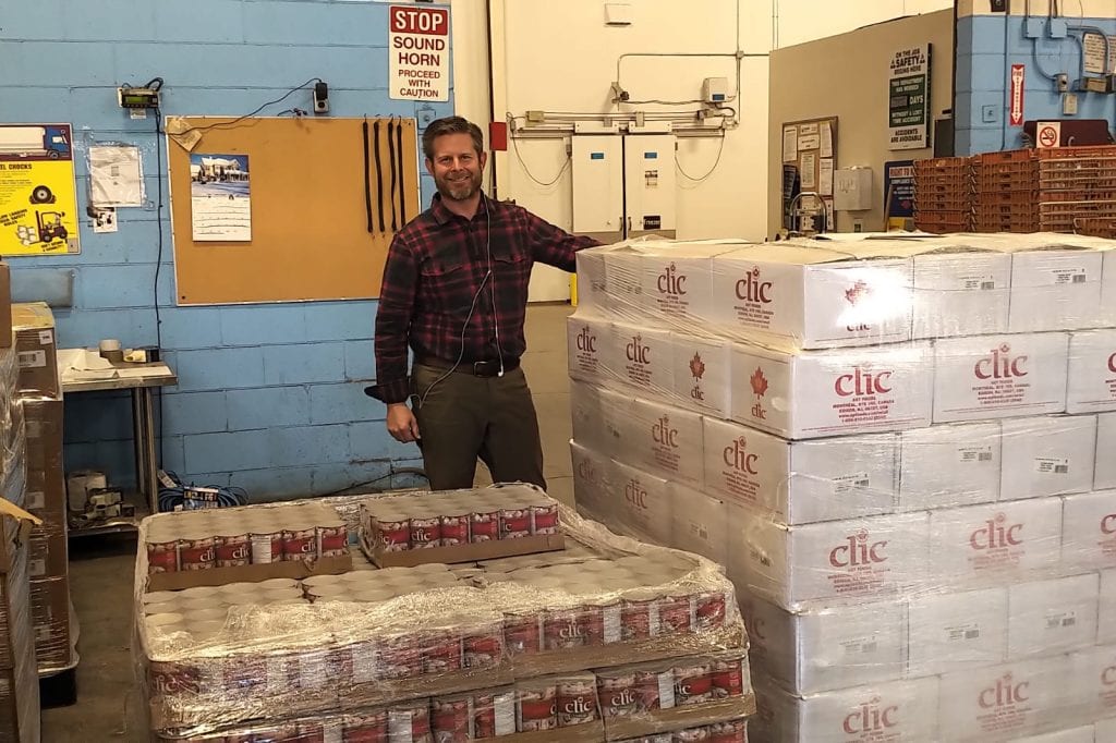 A man standing behind two pallets of dried foods