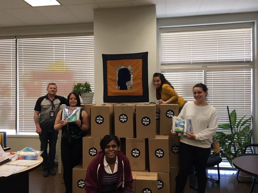 people holding hygiene kits and standing in front of boxes