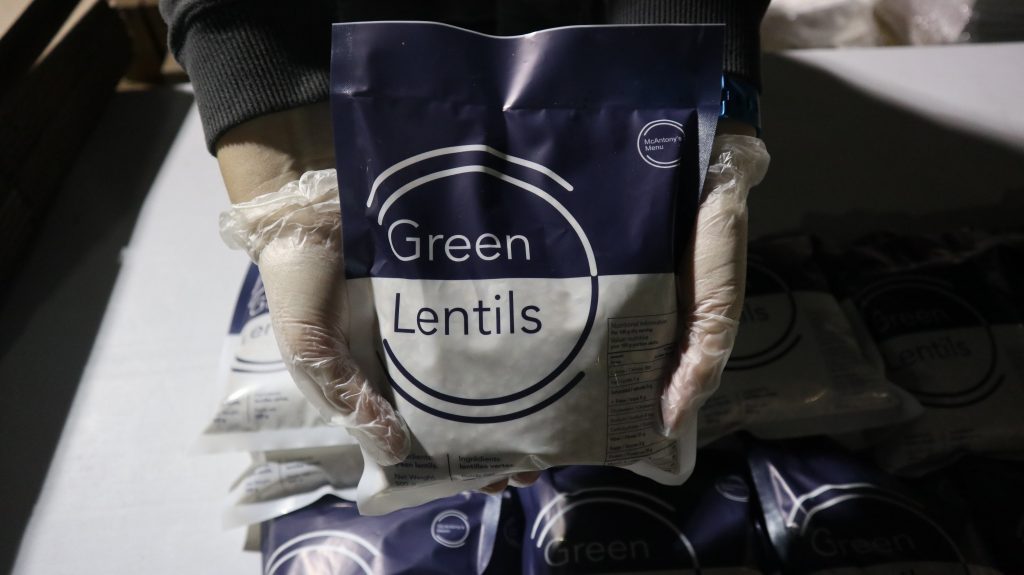 hands holding a 500g bag of packed green lentils in a McAntony's Menu bag