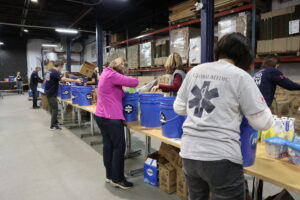Volunteers standing either side of a line of tables packing cleaning supplies into kits for British Columbia floods