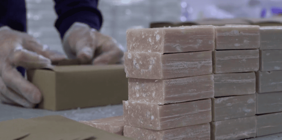 bars of soap stacked in columns, hands wearing gloves in the background